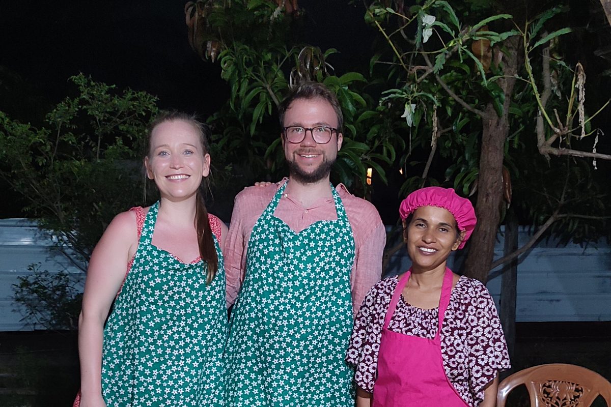 Nimali with two guests in aprons beside the hoppers, roti and curries they cooked together at the Nilaveli cooking class
