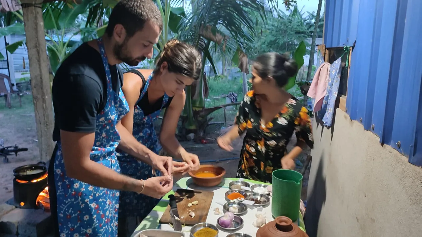 Guests preparing Sri Lankan curry spices in the evening village kitchen