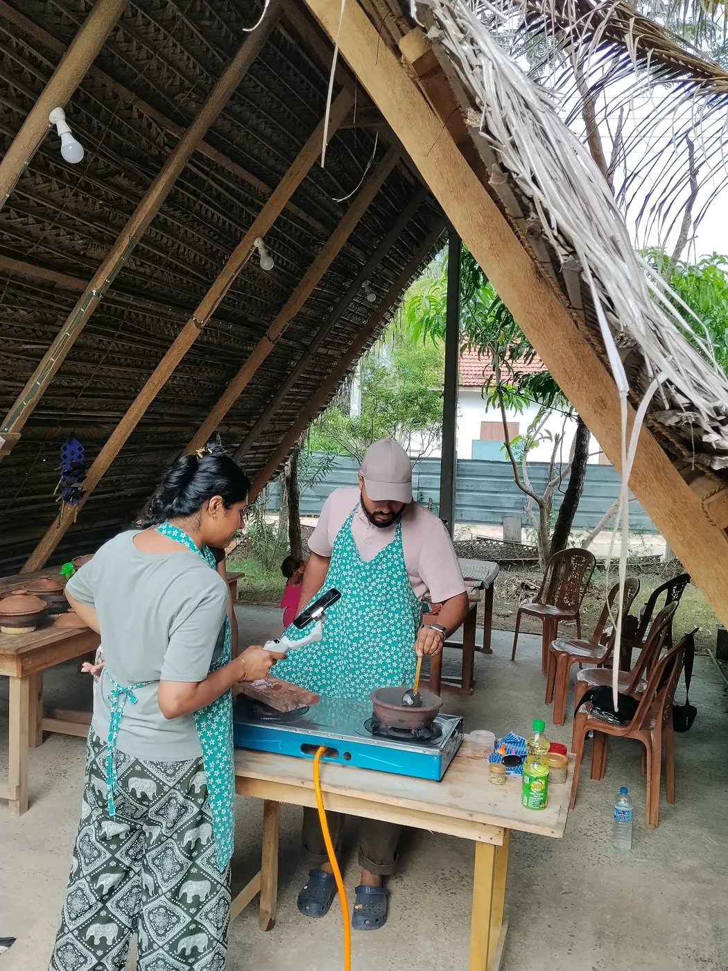 Guests filming their Sri Lankan cooking class experience in the palm leaf kitchen hut