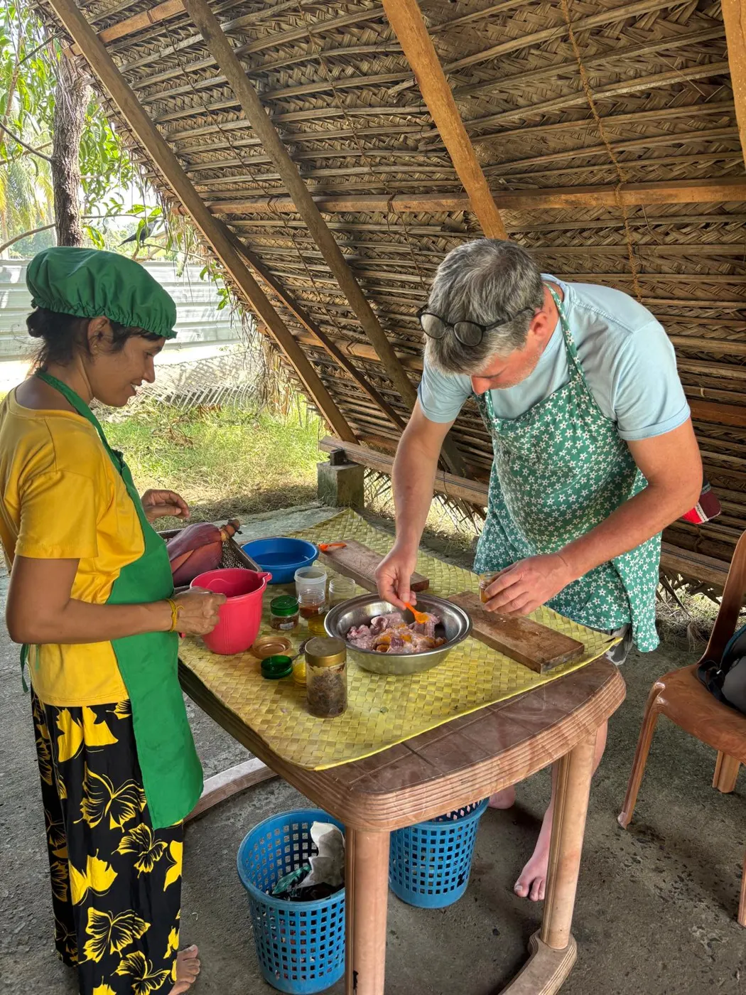 Guest marinating chicken with turmeric under Nimali's guidance in a traditional Sri Lankan kitchen