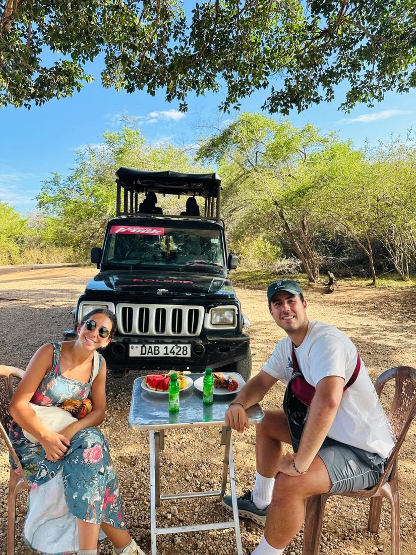 Guests sitting at a table with fruit and cold drinks beside a safari jeep at Udawalawe